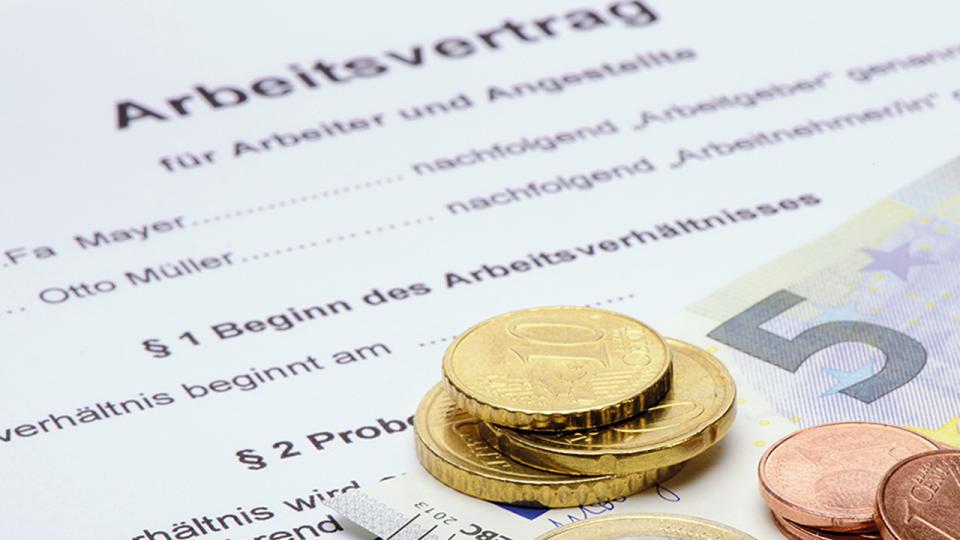 Foto: Arbeitsvertrag mit daraufliegenden Münzen und einem Geldschein